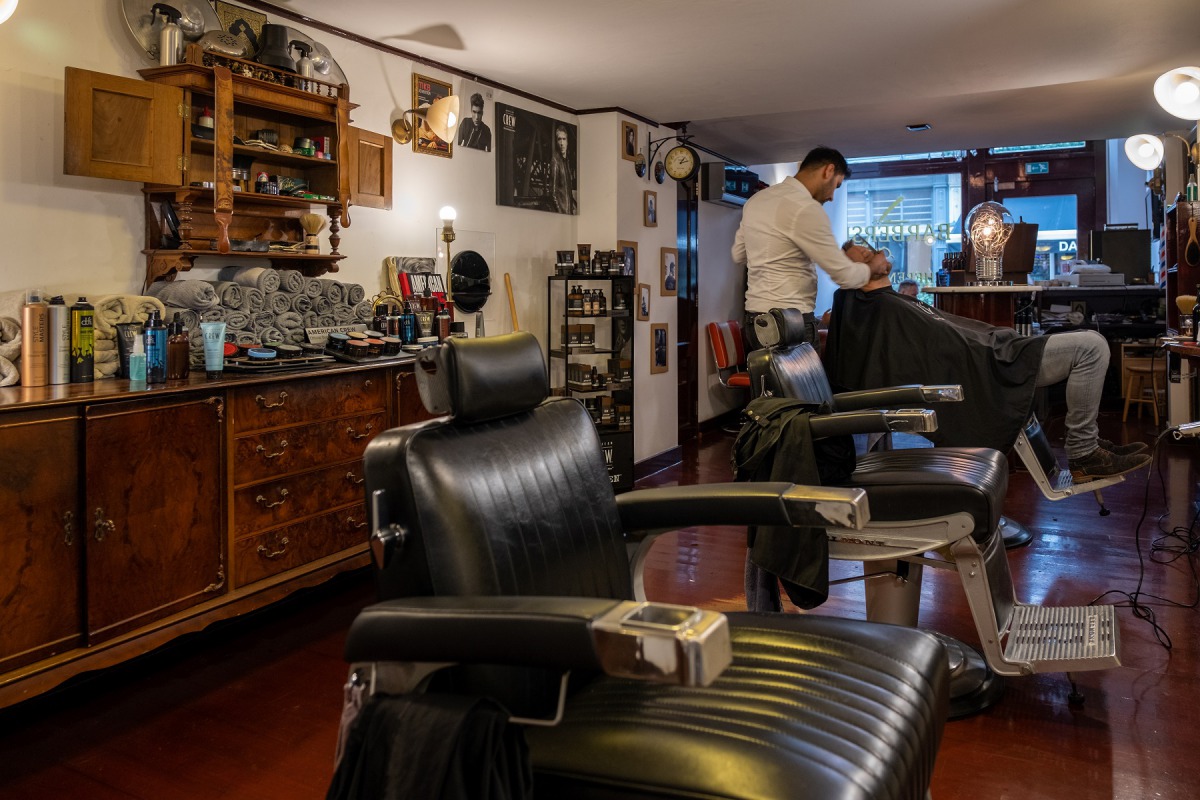 Barbier aan het werk met klant in lederen stoel